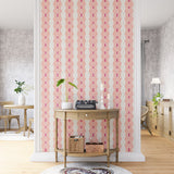 A maximalist living space with an accent wall papered in an intricate diamond stripe print in pink, orange and cream.