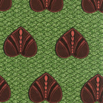 Detail of fabric in a geometric heart print in maroon and black on a green field.