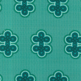 Detail of fabric in a repeating curvilinear knot print in blue and turquoise on a turquoise field.