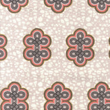 Detail of fabric in a repeating curvilinear knot print in coral and gray on a cream field.