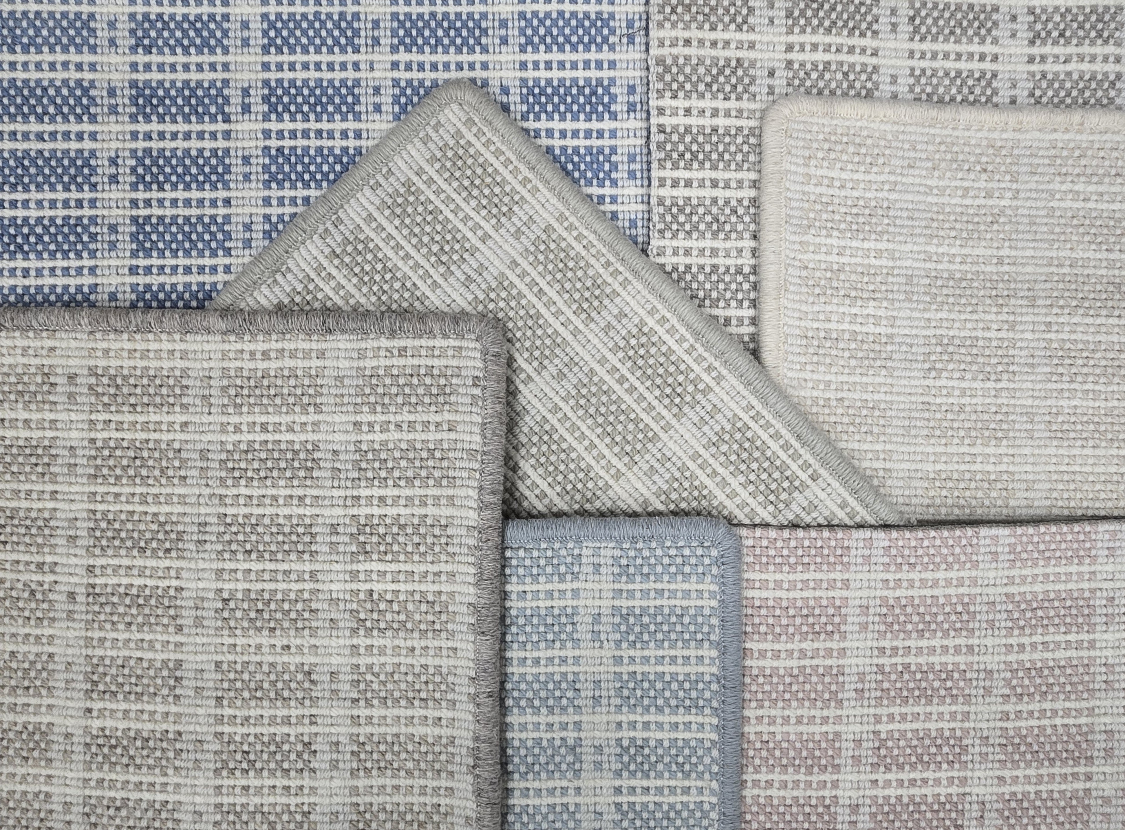 Broadloom carpet samples in a slim check pattern in a range of blue, grey and pink.