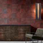 A modernist living tableau with gray furniture and a wall papered in square leather tiles in mottled oxblood and gray.