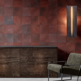 A modernist living tableau with gray furniture and a wall papered in square leather tiles in mottled oxblood and gray.