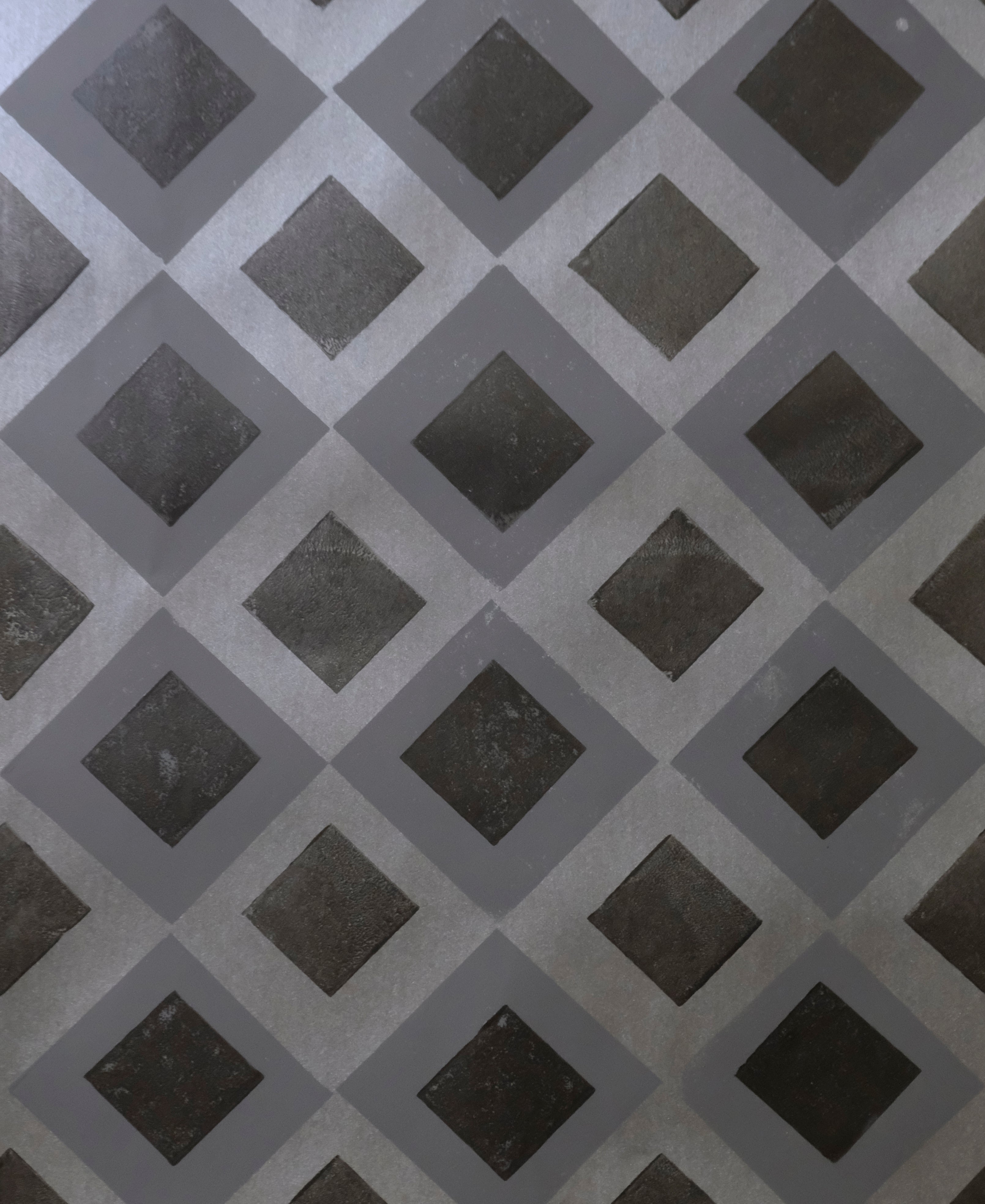 Detail of wallpaper in a diamond lattice print in shades of gray and charcoal.