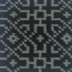 Close-up of a textured rug with a geometric pattern in turquoise on black