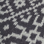 Close-up of a textured rug with a geometric pattern in turquoise on black