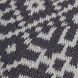 Close-up of a textured rug with a geometric pattern in turquoise on black