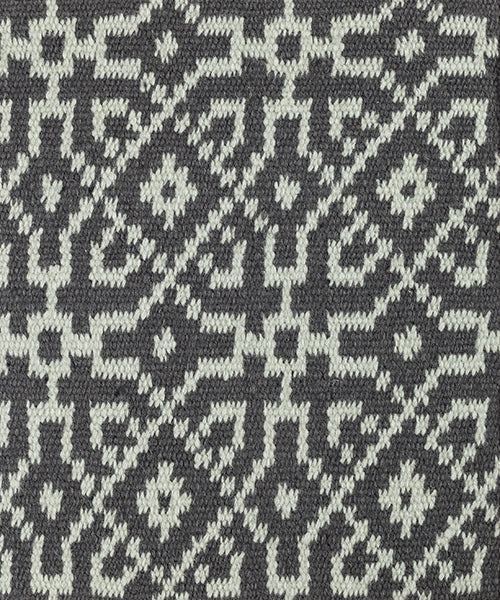 Close-up of a textured rug with a geometric pattern in turquoise on black