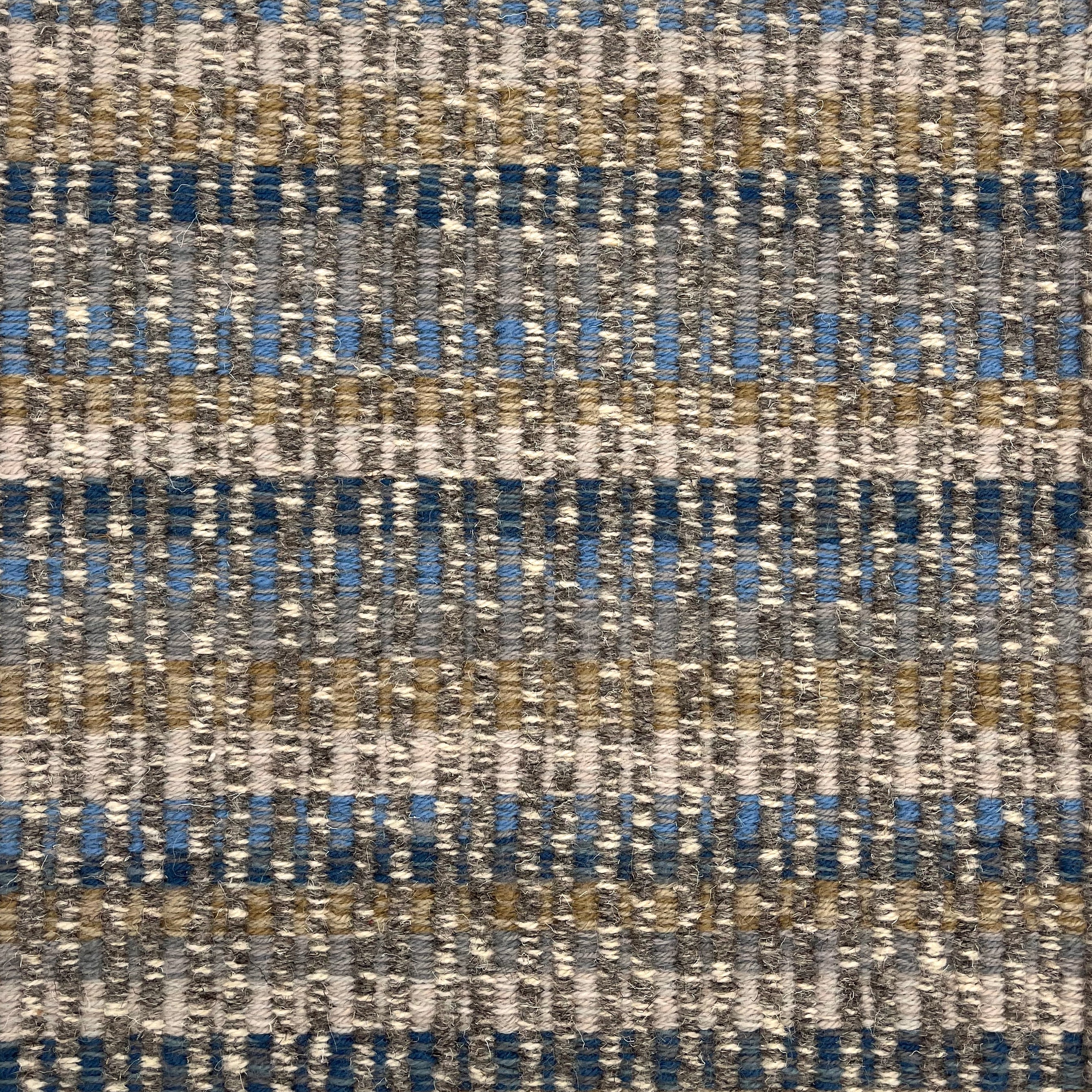 Handwoven rug detail in a textural design in blue, tan and cream