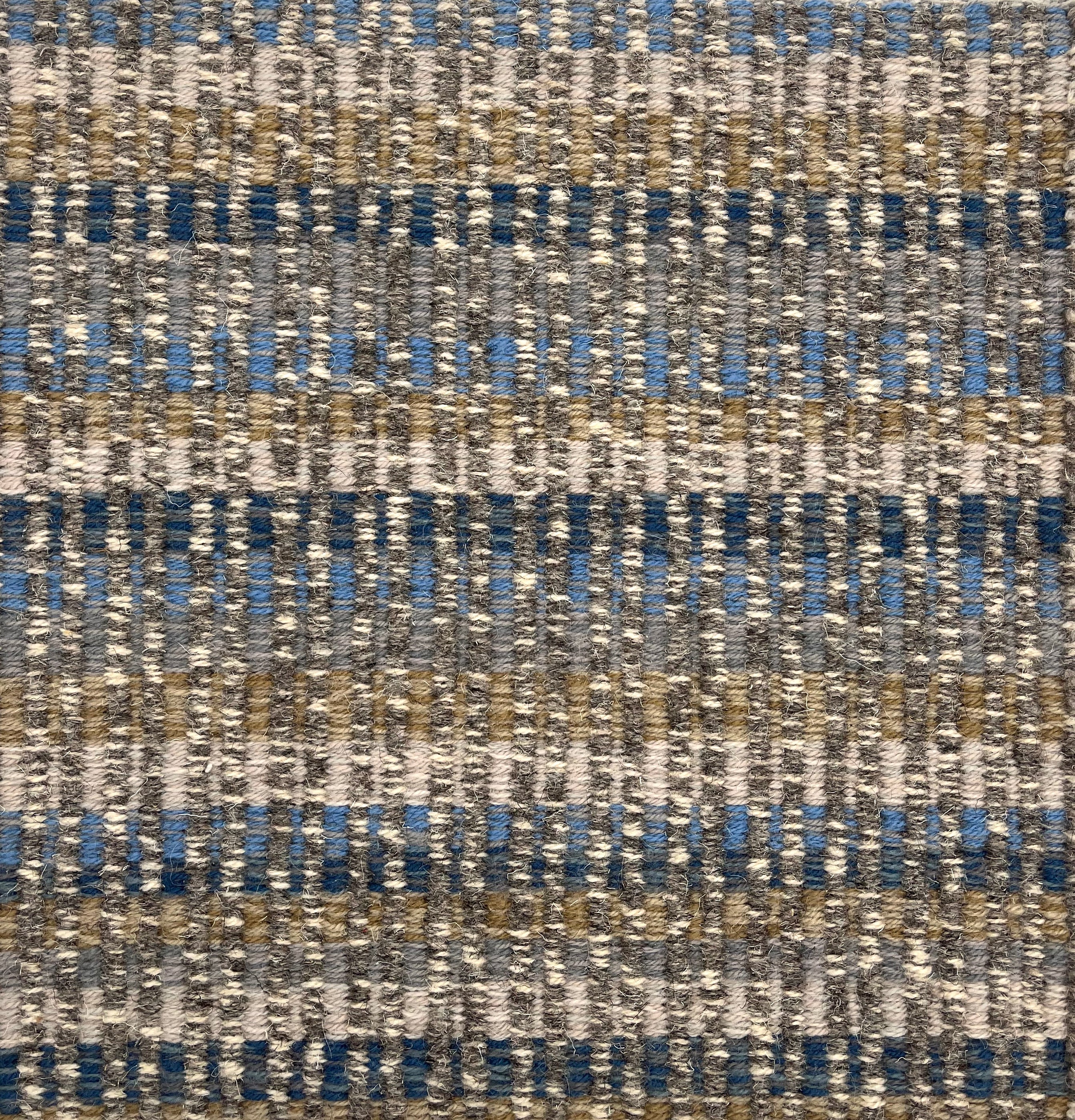 Handwoven rug detail in a textural design in blue, tan and cream