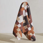 A large piece of draped fabric in an interlocking square pattern in shades of brown, rust and cream.