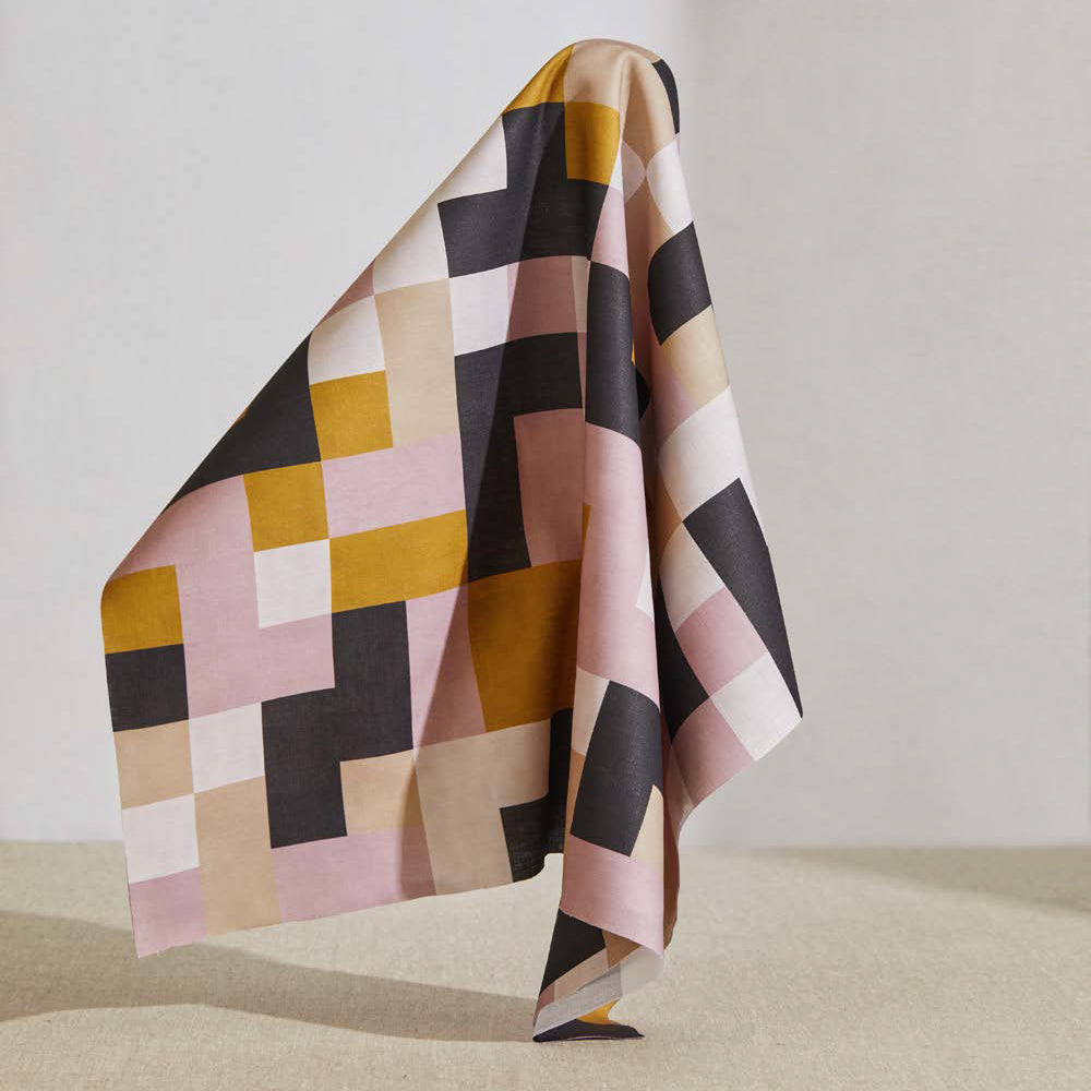 A large piece of draped fabric in an interlocking square pattern in shades of pink, purple, mustard and cream.