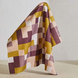 A large piece of draped fabric in an interlocking square pattern in shades of purple, mustard and cream.