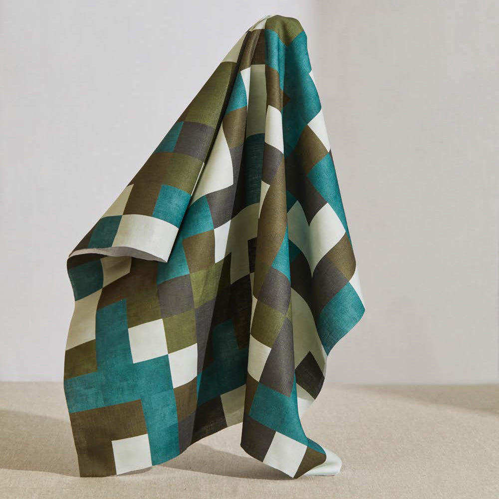 A large piece of draped fabric in an interlocking square pattern in shades of blue, green, gray and cream.