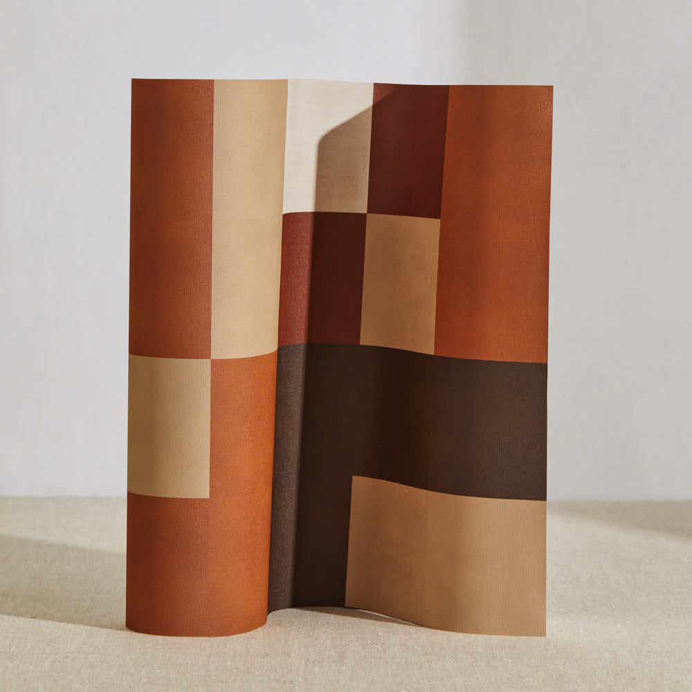 A curved partition stands on the ground, covered in an interlocking square pattern in shades of brown, rust and cream.
