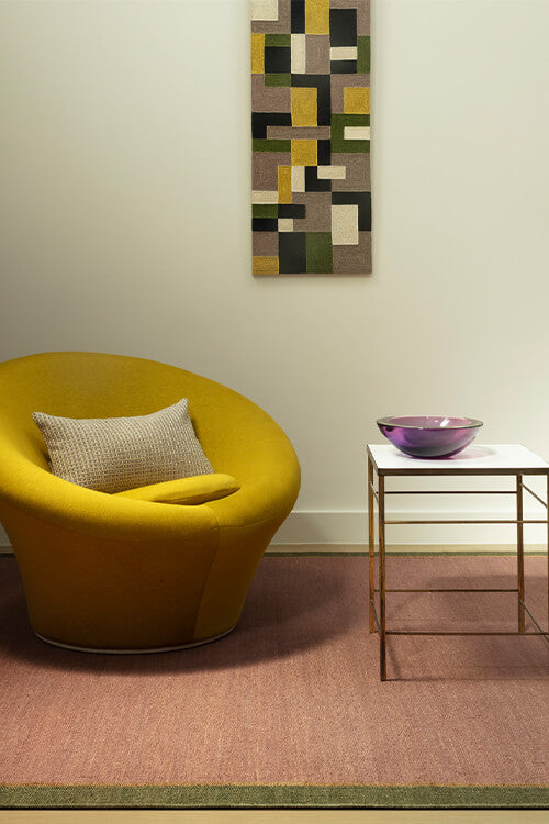 Yellow chair with a textured pillow in a room with a abstract patterned wall art.
