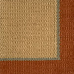 Close up of a flatweave rug in tan with a blue and coral border. 