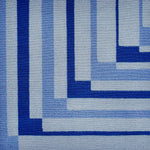 Detail of a handknotted rug in a graphic geometric design in shades of a blue.