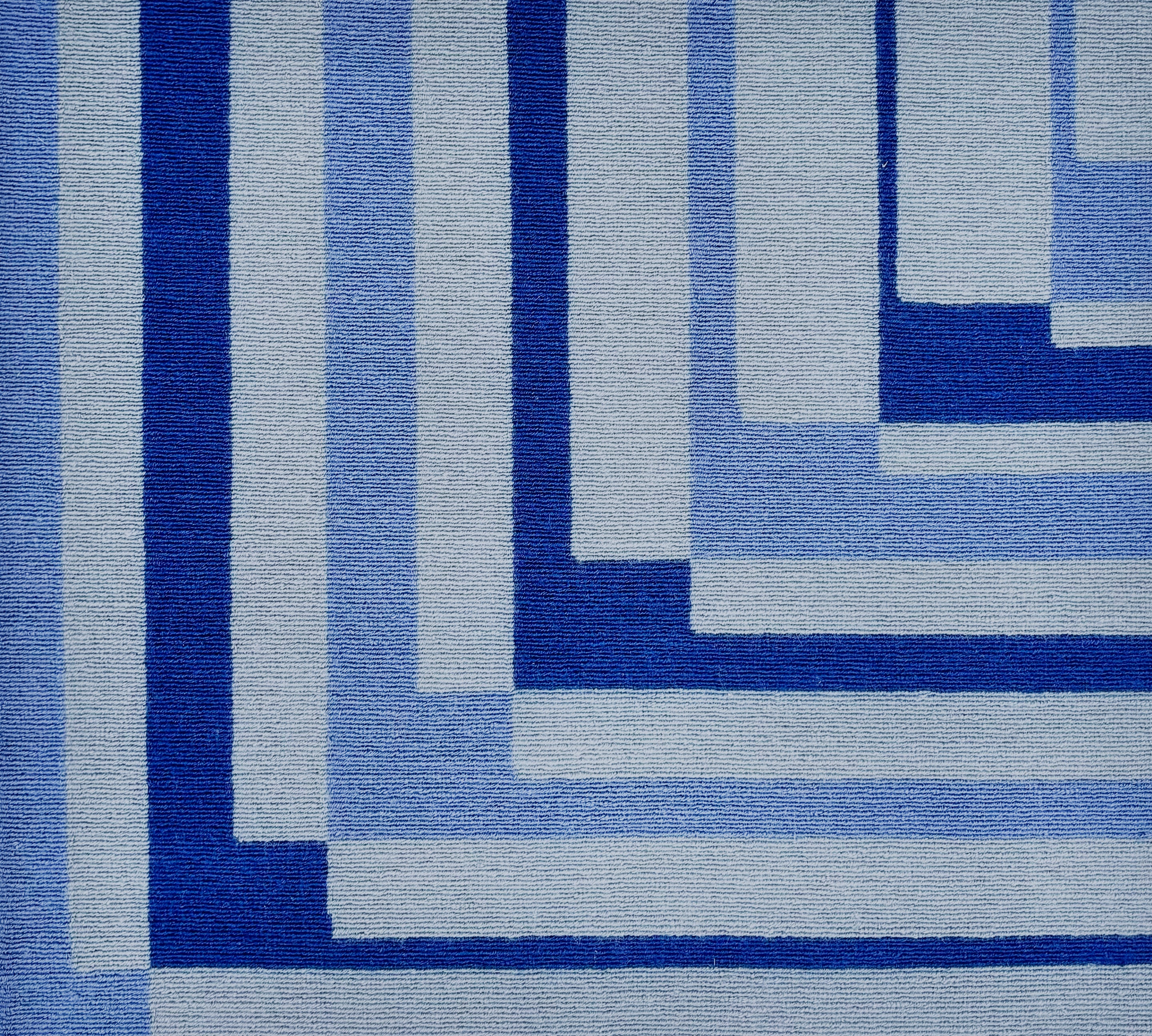 Detail of a handknotted rug in a graphic geometric design in shades of a blue.