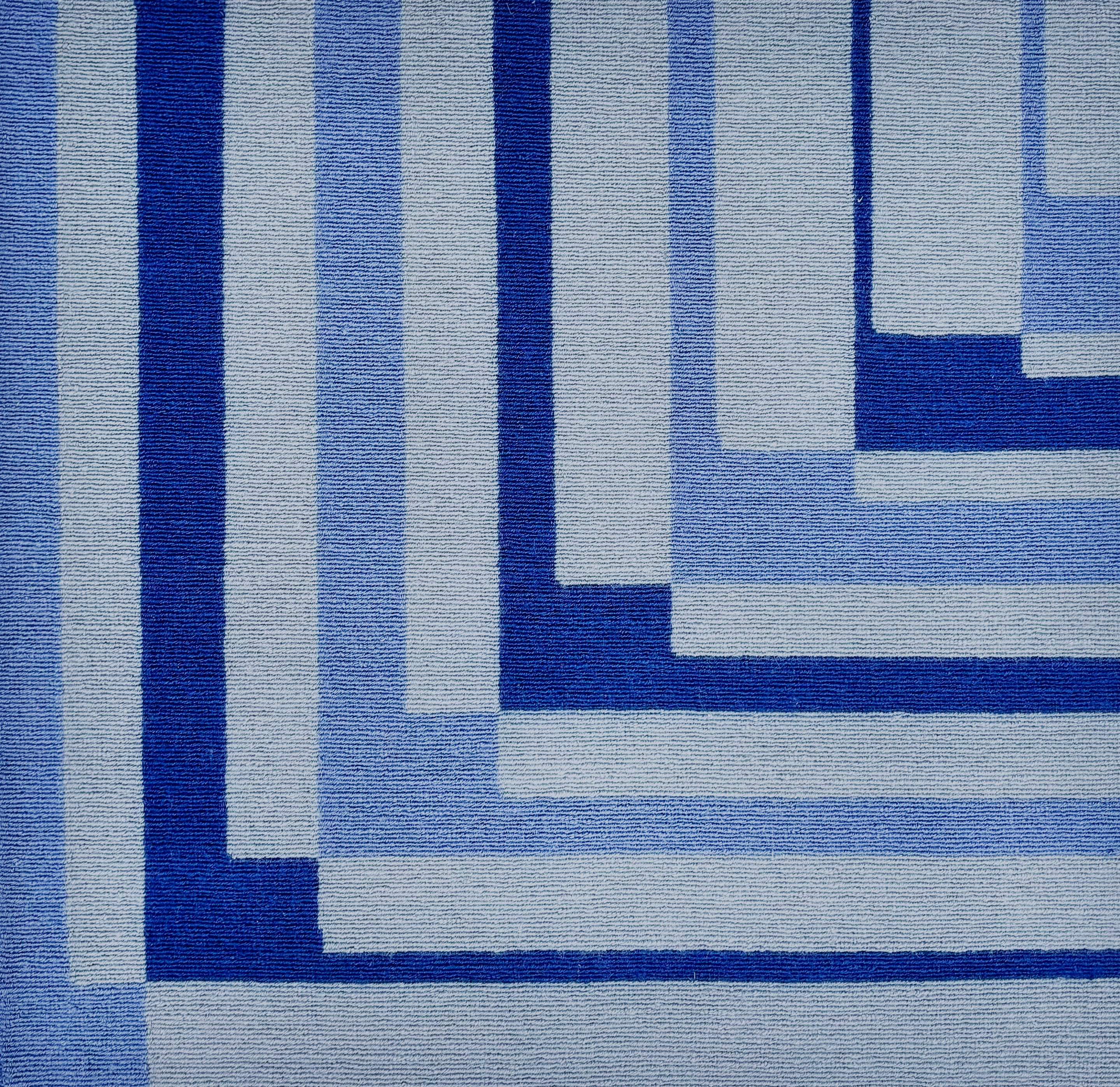 Detail of a handknotted rug in a graphic geometric design in shades of a blue.