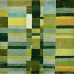 Detail of a handknotted rug in a dense geometric design in shades of a green and accents of yellow