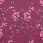 Detail of fabric in an embroidered floral print in black and pink on a maroon field.