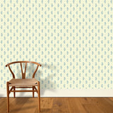 A wooden chair stands in front of a wall papered in a floral paisley print in blue on a light yellow field.