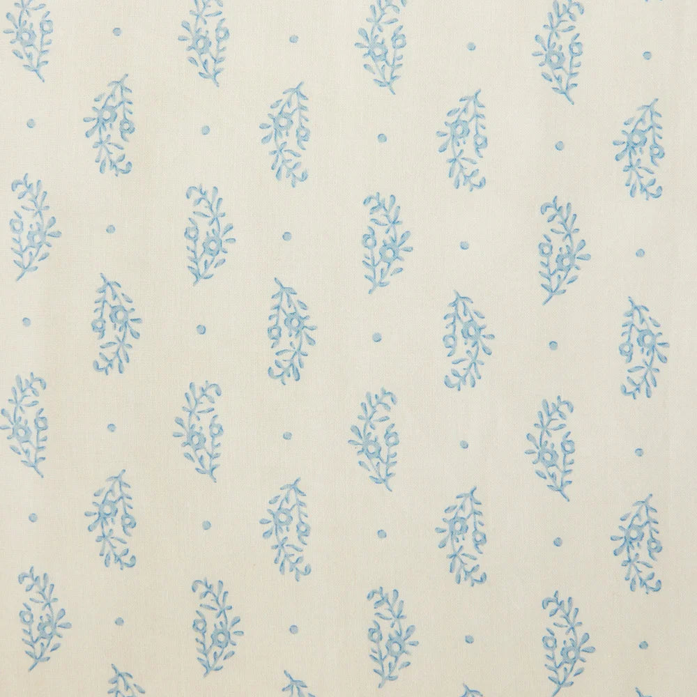 Detail of fabric in a floral paisley print in blue on a cream field.