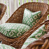 A cluster of wicker armchairs with cushions upholstered in a playful floral grid print in green, orange and white.