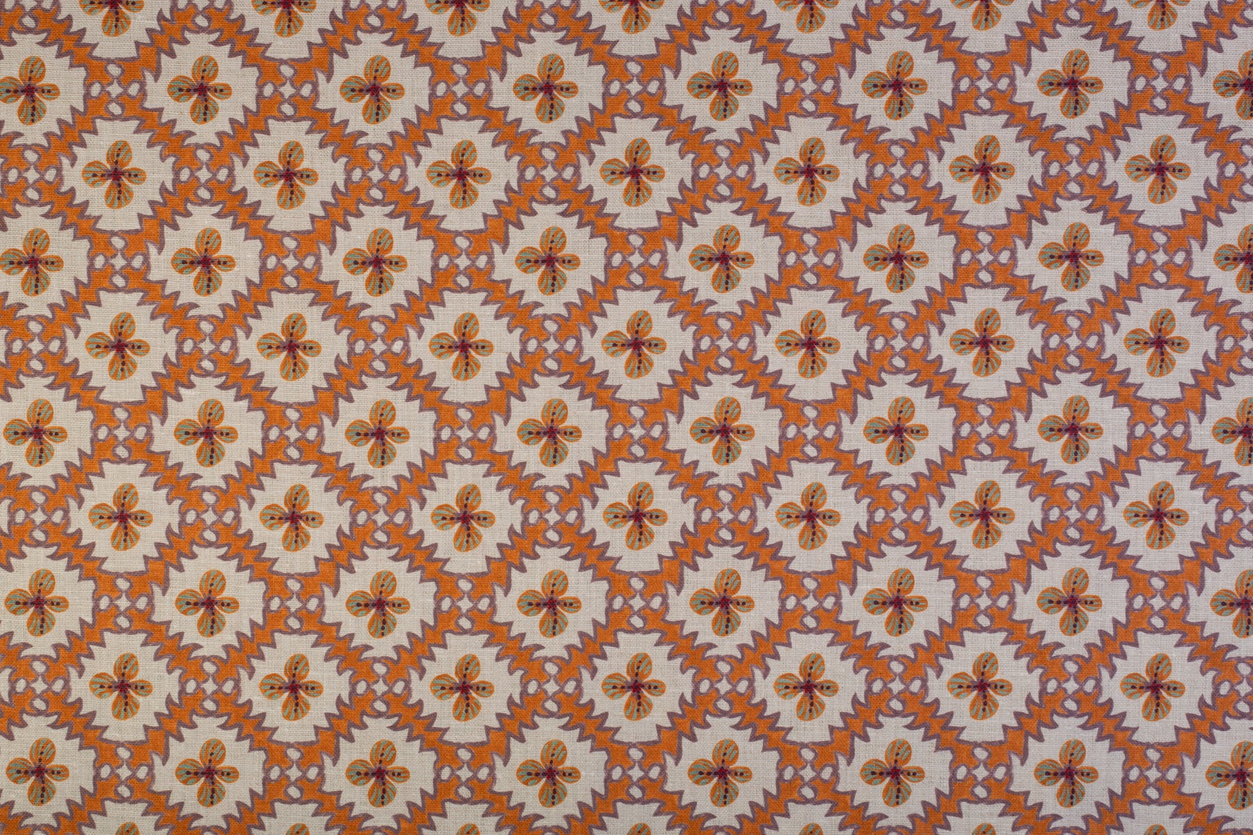 Detail of fabric in a playful floral grid print in orange, purple and green on a white field.