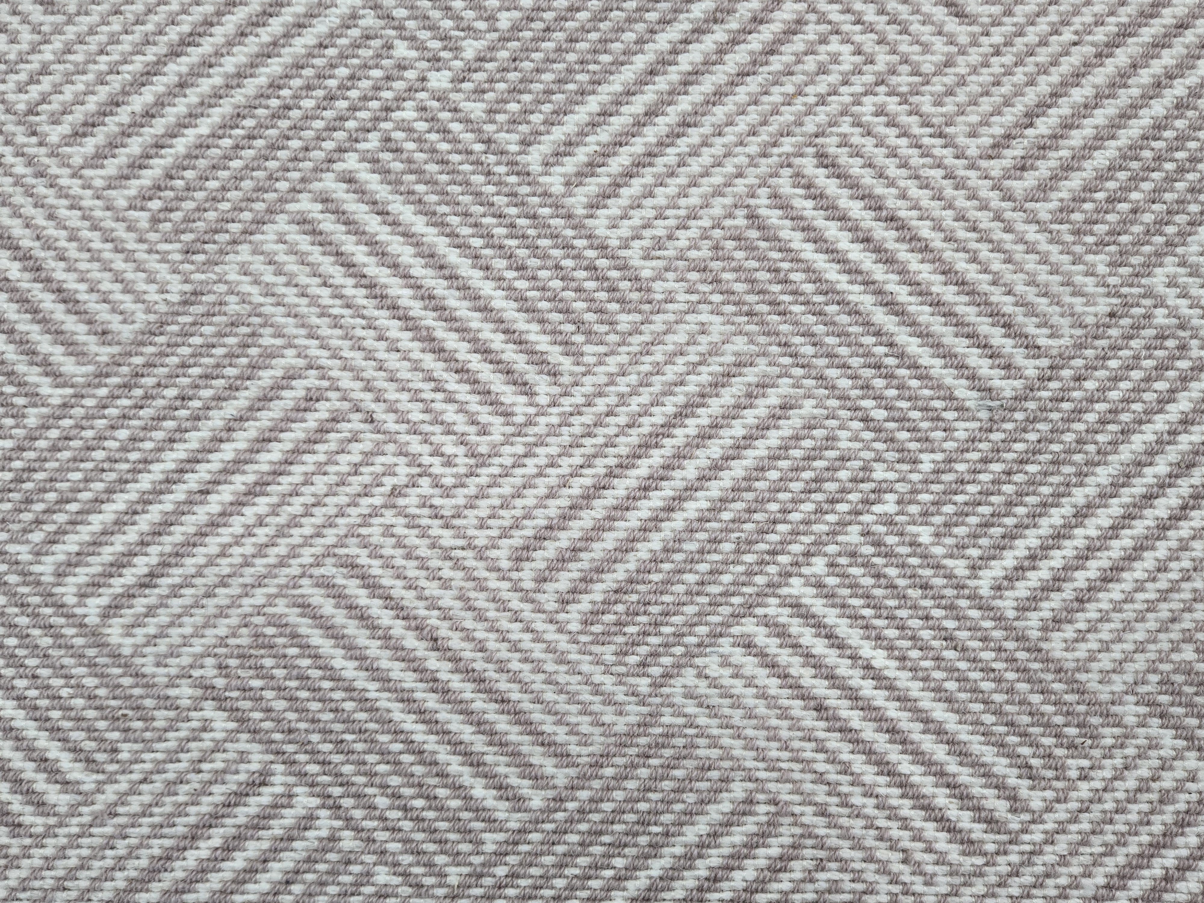 Broadloom rug sample in a diamond pattern in stripes of white and mauve.