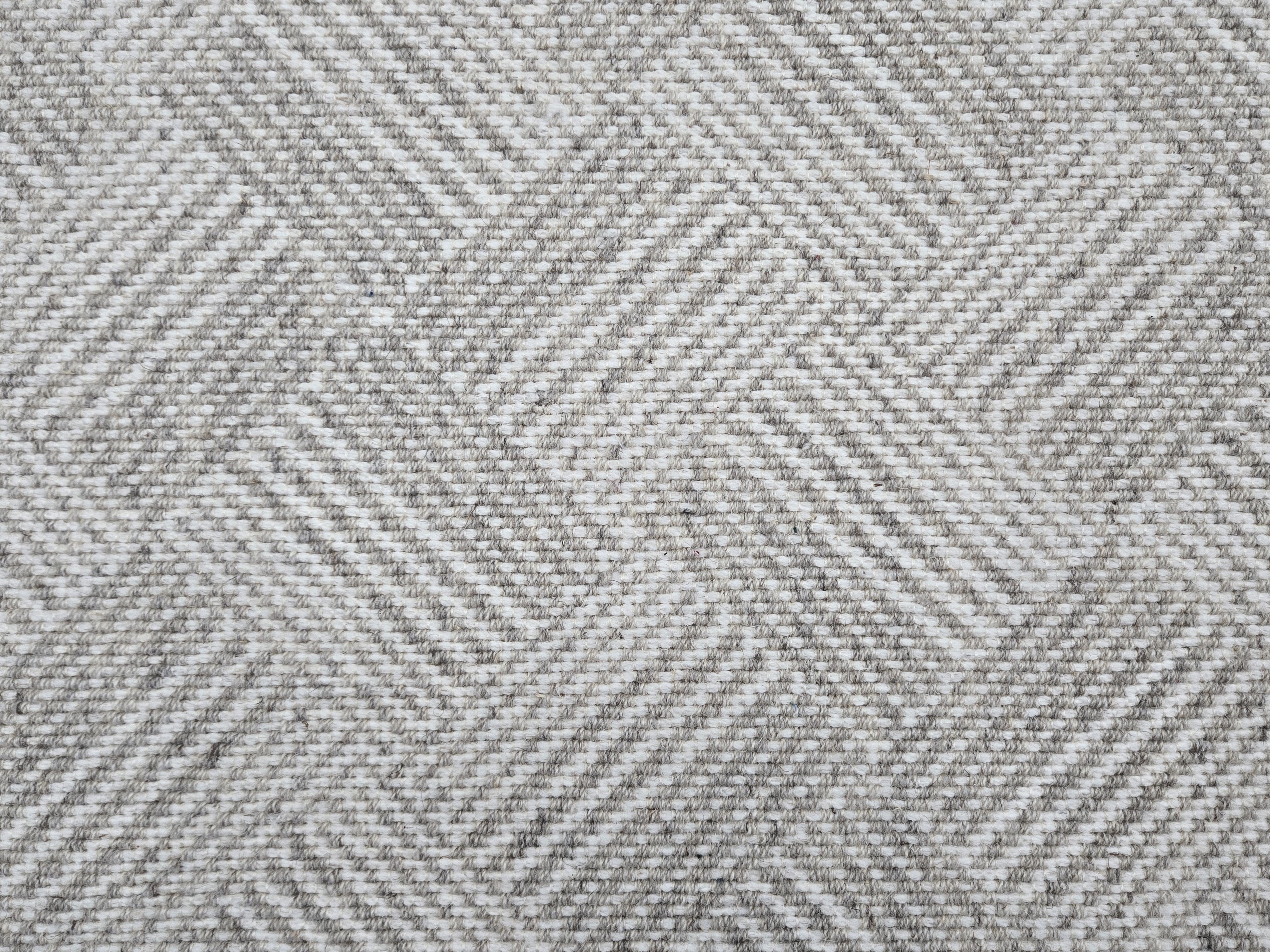 Broadloom rug sample in a diamond pattern in stripes of white and grey.