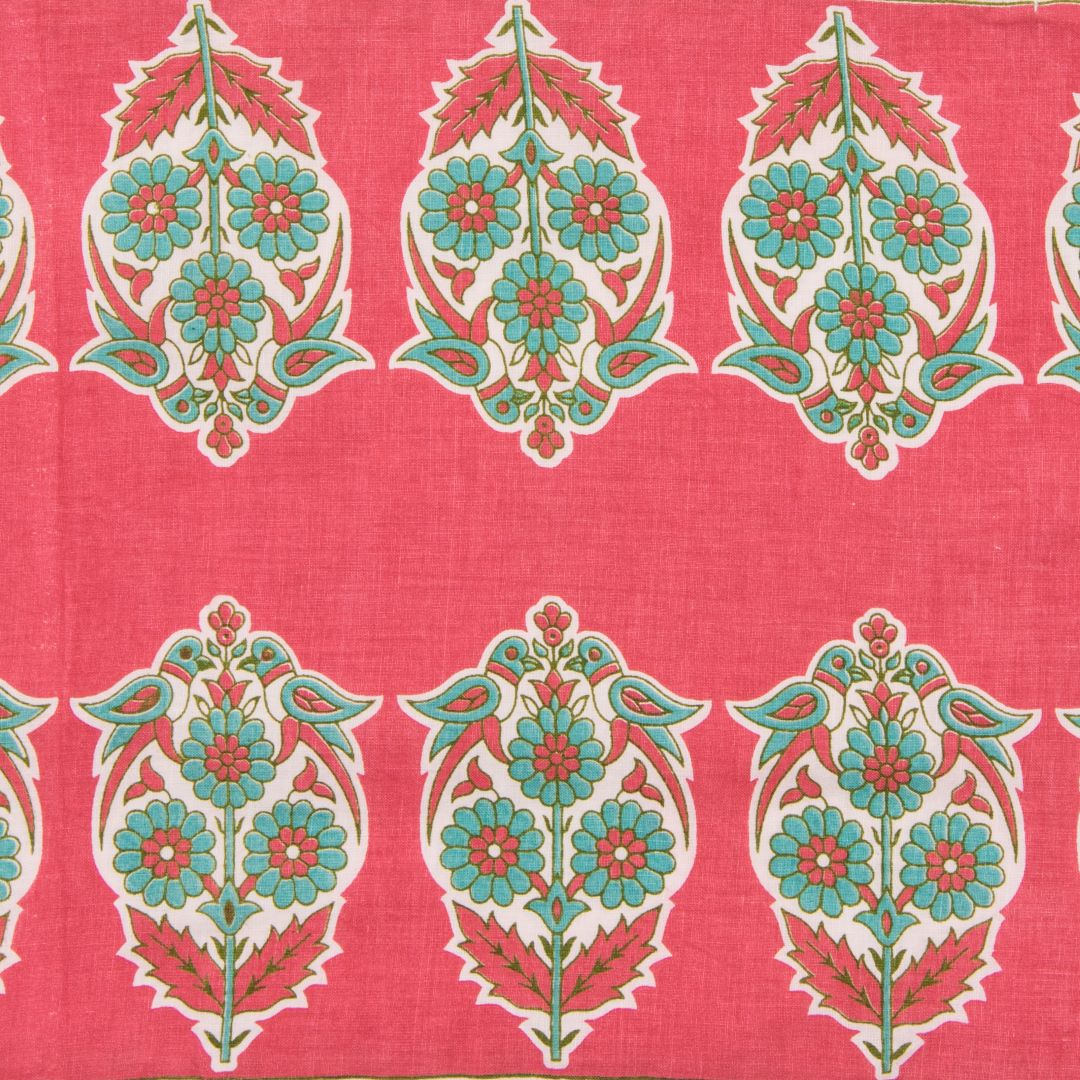 Detail of fabric in a repeating bird and floral paisley in turquoise, cream and red on a red field.
