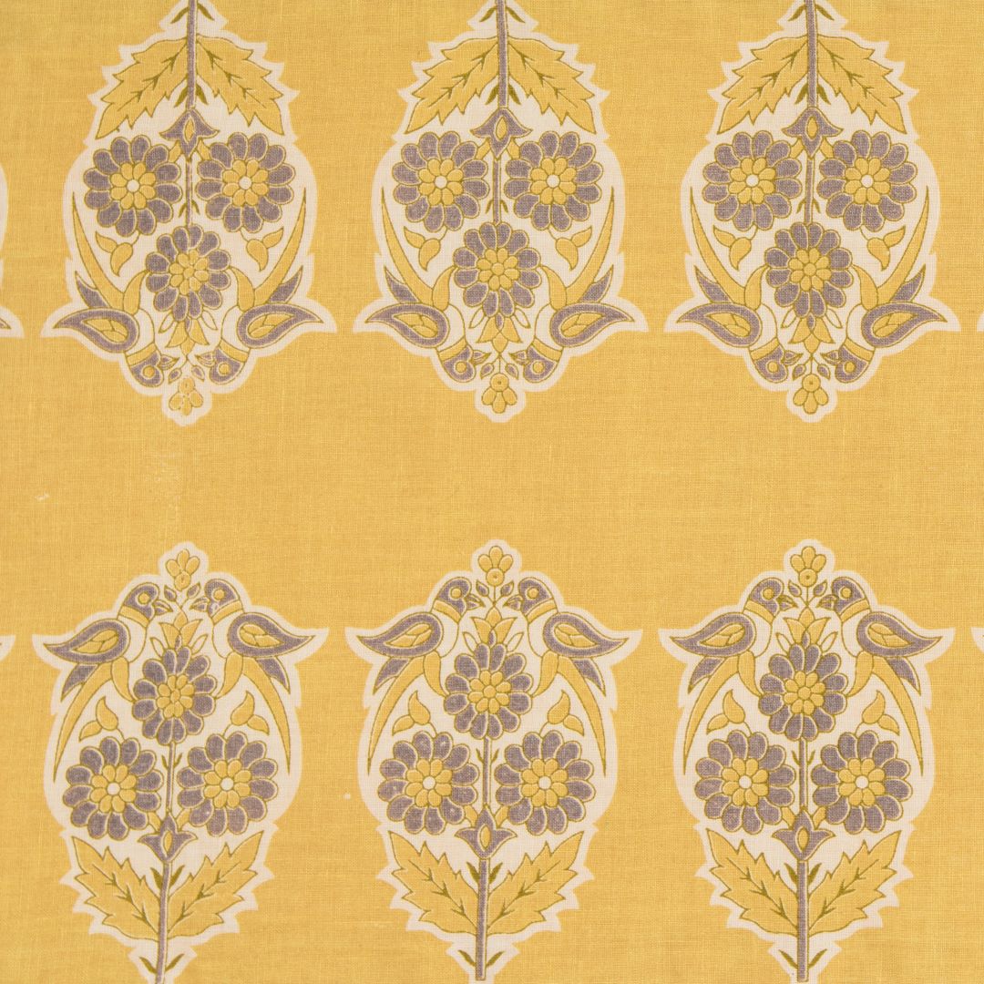 Detail of fabric in a repeating bird and floral paisley in purple, cream and yellow on a yellow field.