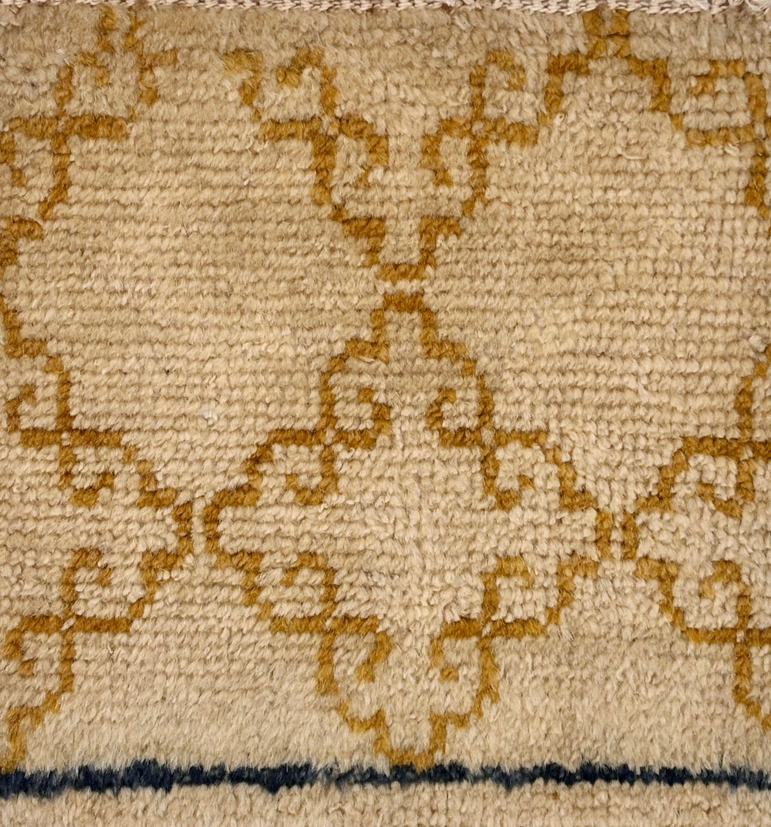 Handknotted rug sample with an ochre filigree design on a beige field.