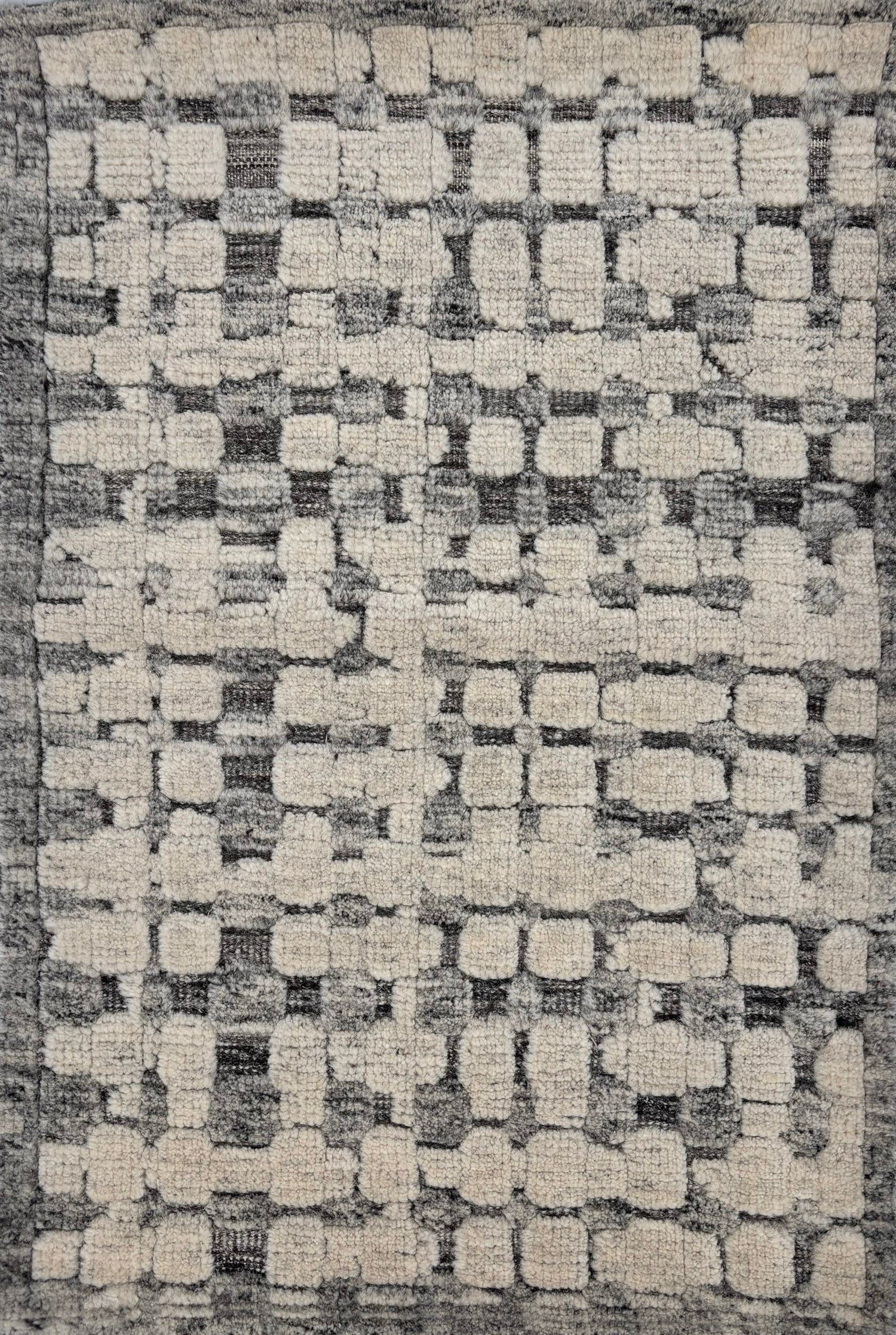 Handknotted rug sample in a textural geometric pattern in grey and ivory.