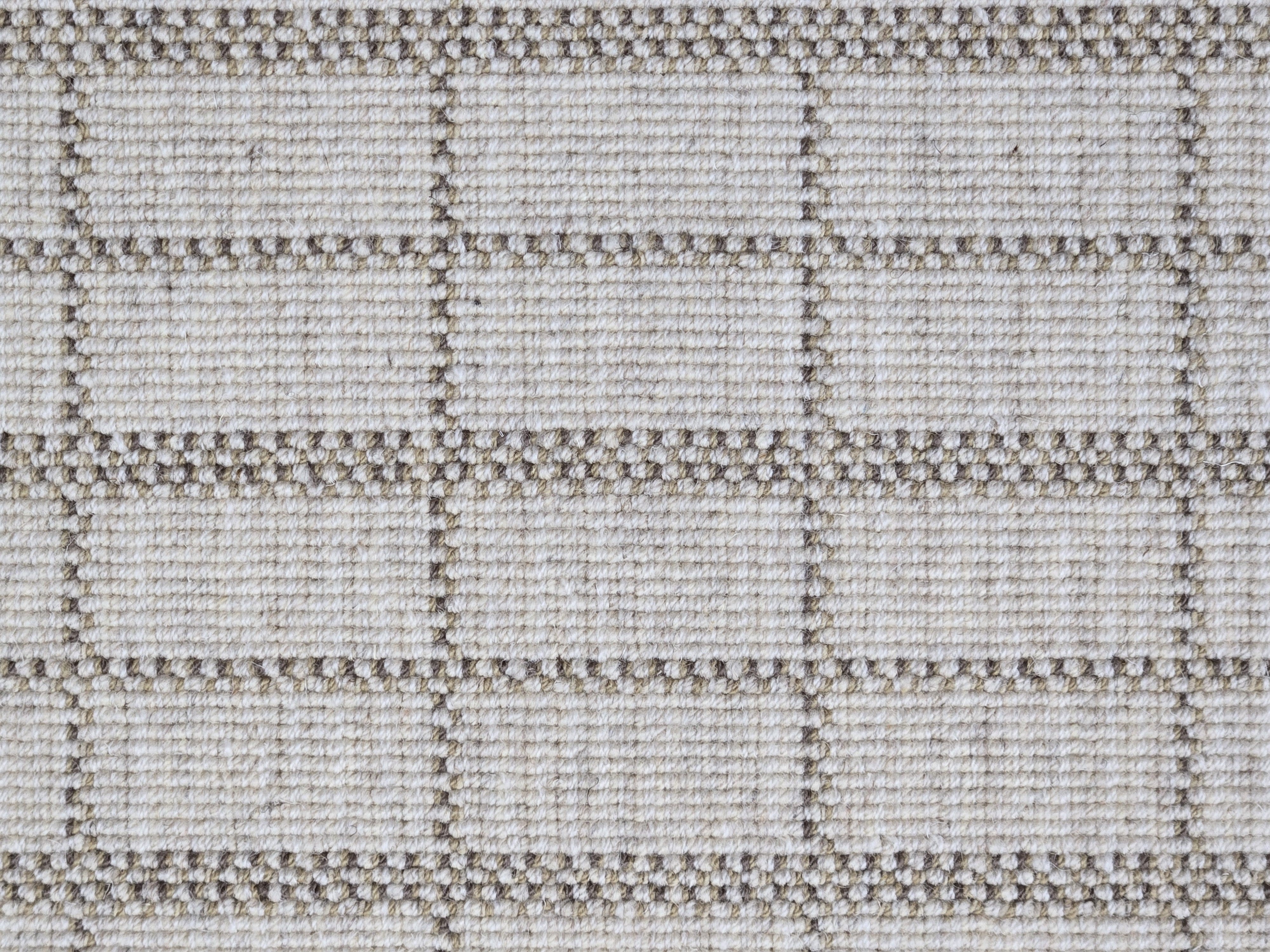 Broadloom carpet detail in plaid grid in shades of brown on a beige field.