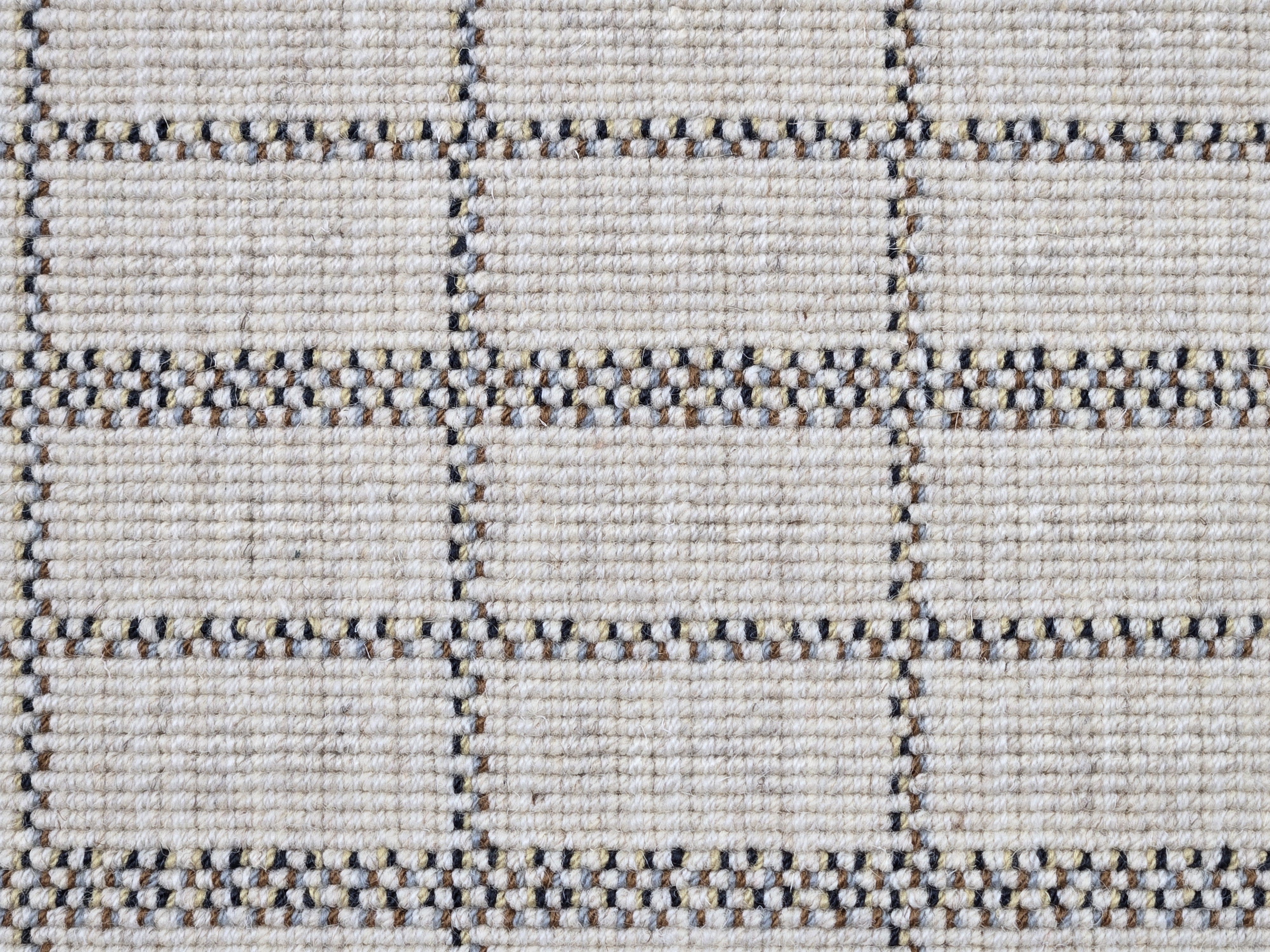 Broadloom carpet detail in plaid grid in shades of blue and brown on a beige field.