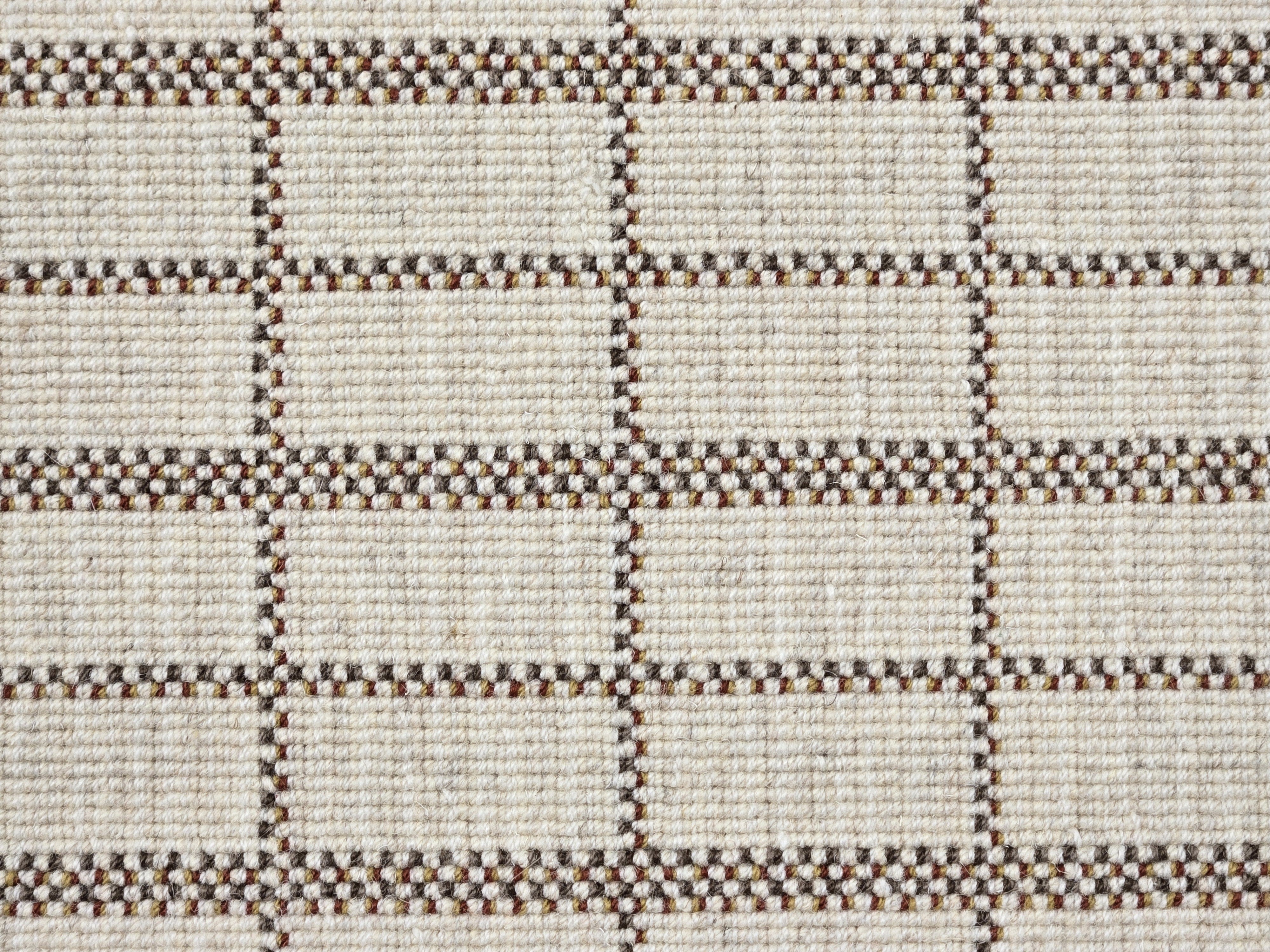 Broadloom carpet detail in plaid grid in shades of burnt sienna on a beige field.