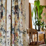 A cozy living space with plants and long curtains in a painterly floral print.