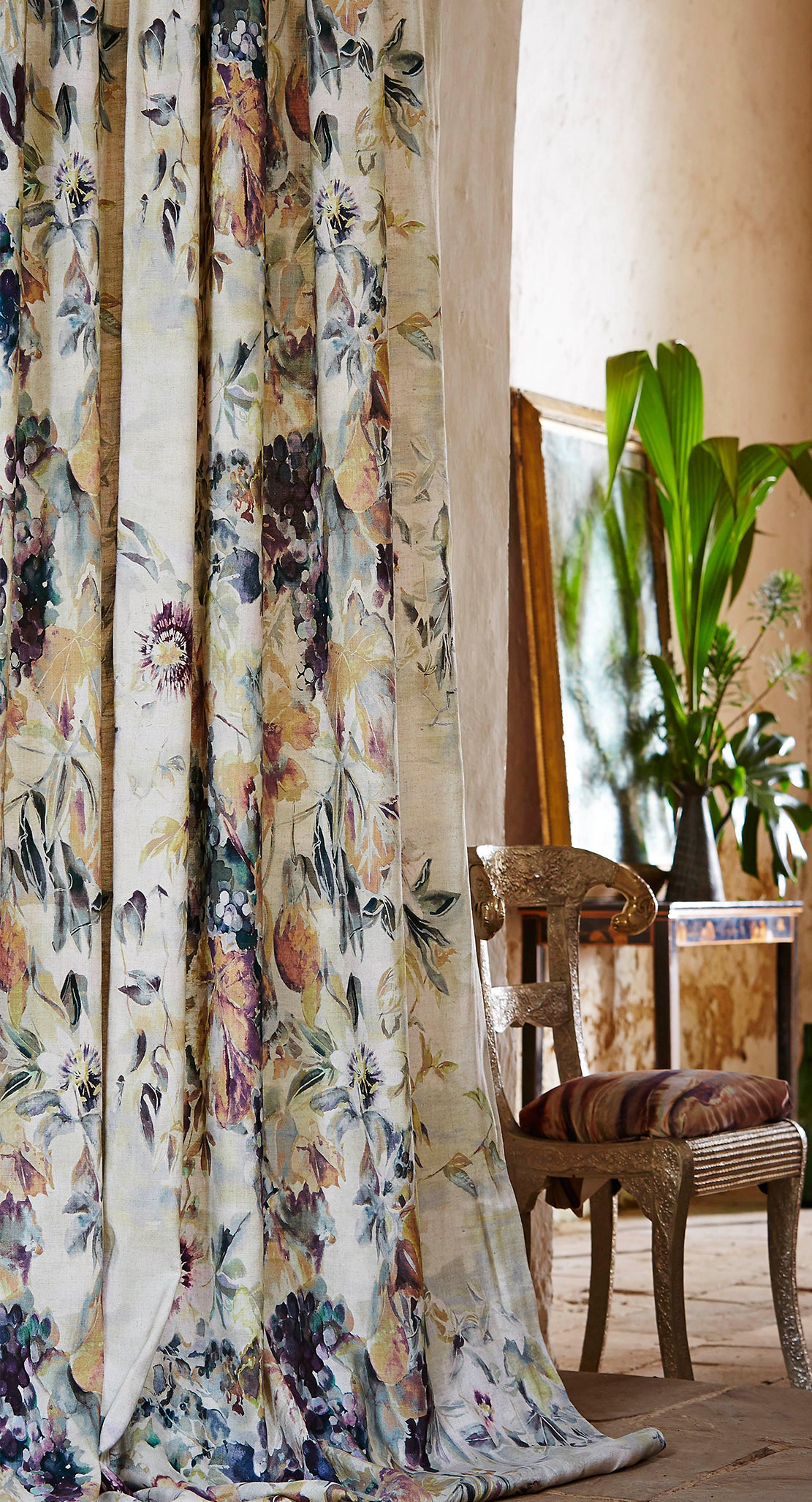 A cozy living space with plants and long curtains in a painterly floral print.