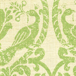 Detail of fabric in a botanical and bird print in green on a cream field.