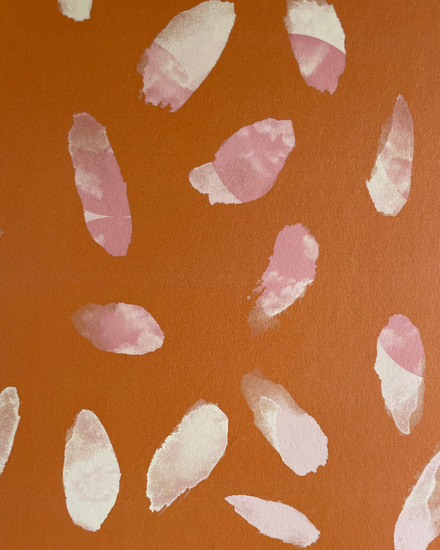 Detail of wallpaper in a playful paint blotch print in shades of pink and cream on an orange field.