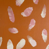 Detail of wallpaper in a playful paint blotch print in shades of pink and cream on an orange field.