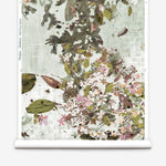 Roll of floral wallpaper with green leaves and pink flowers on a light background