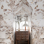 Small bedroom with floral wallpaper, wooden dresser, and bed.