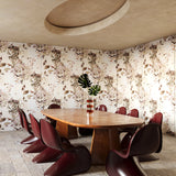 Dining area with a wooden table and red chairs against a floral wallpaper in beige tones.