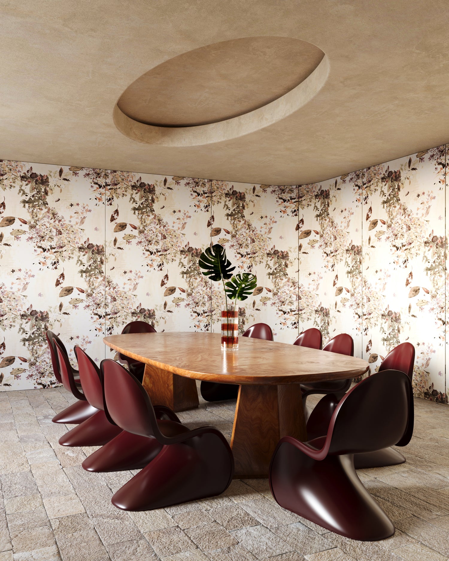 Dining area with a wooden table and red chairs against a floral wallpaper in beige tones.