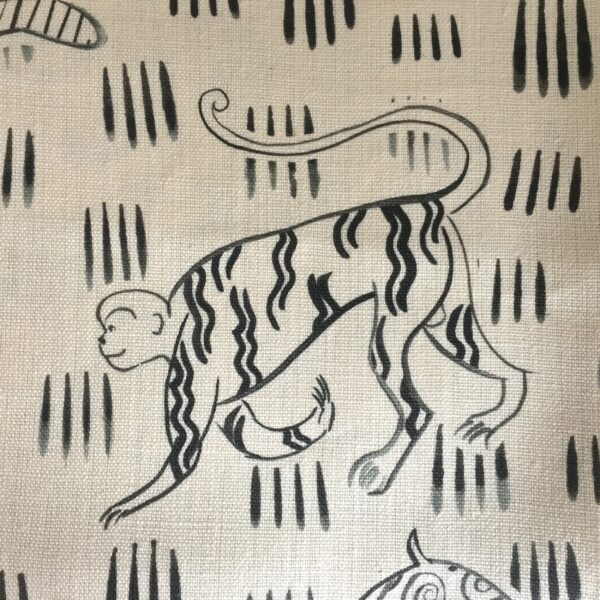 Fabric in a repeating painterly animal and dash print in black on a cream field.