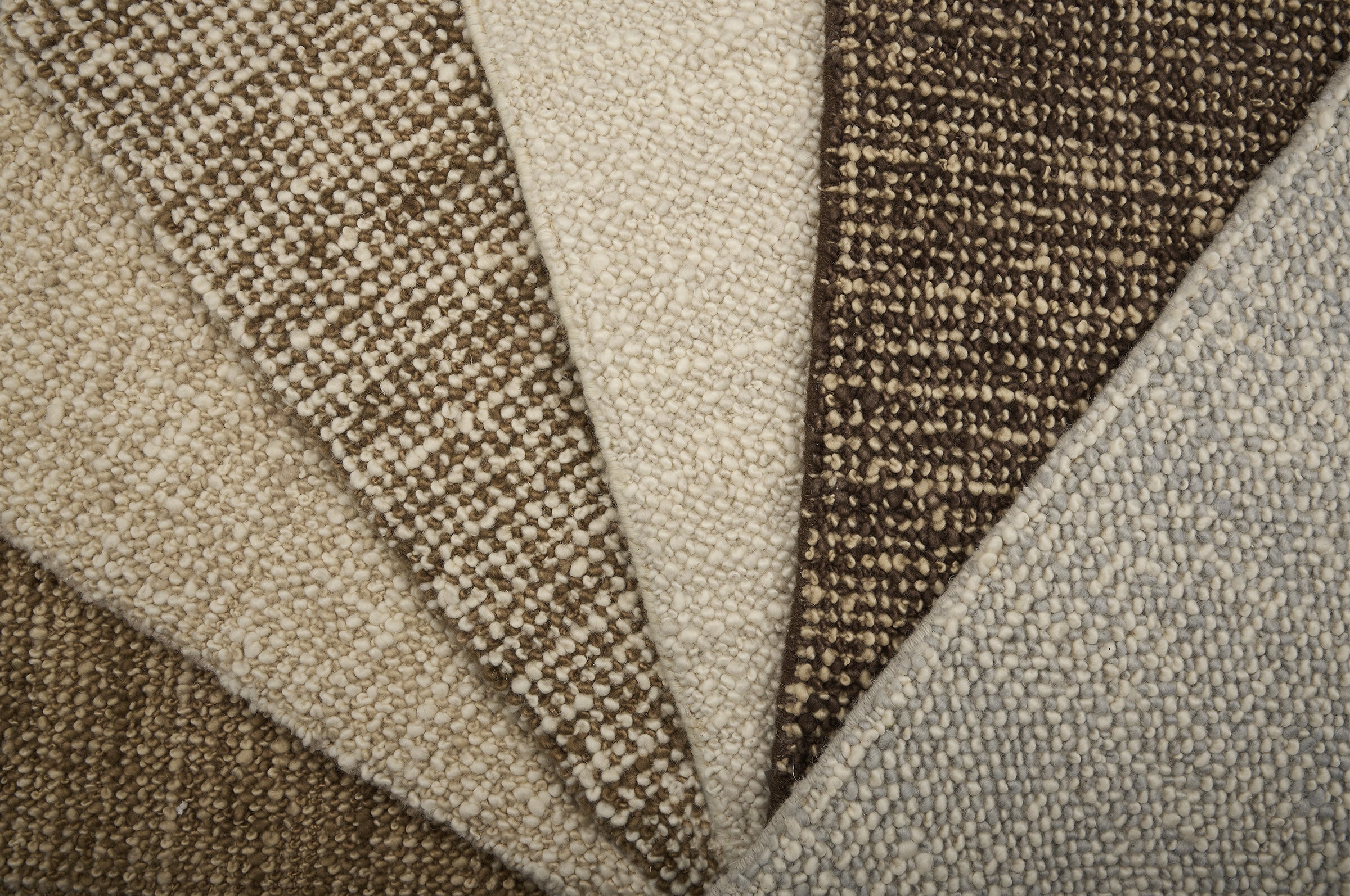 Close-up of textured carpet swatches in beige, brown, and gray.